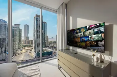 a living room with a large tv and a large window at Daniels 2BR at Liv Marina with Marina View in Dubai