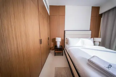 a bedroom with a large white bed and wooden cabinets at Luxury 1 Bedroom Canalfront Apartment with Burj Khalifa Views from Resort-Style Pool - Walk to Jumeirah Beach in Dubai