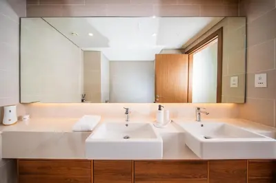 a bathroom with two sinks and a large mirror at Luxury 1 Bedroom Canalfront Apartment with Burj Khalifa Views from Resort-Style Pool - Walk to Jumeirah Beach in Dubai