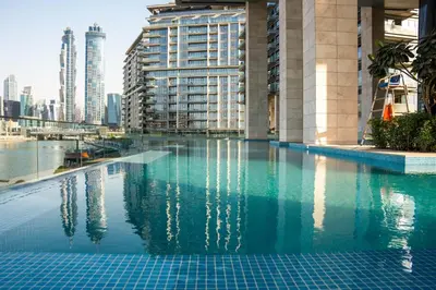 a pool in the middle of a city with buildings at Luxury 1 Bedroom Canalfront Apartment with Burj Khalifa Views from Resort-Style Pool - Walk to Jumeirah Beach in Dubai