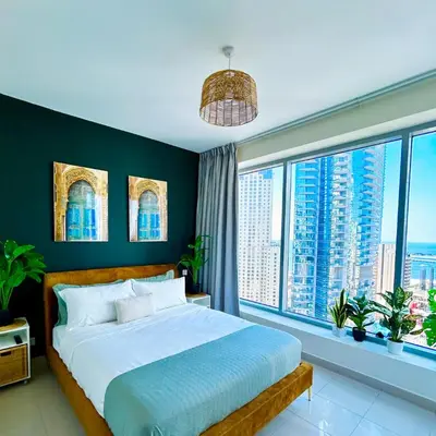 a bedroom with a large bed and large windows at Marina Oasis JBR Beach in Dubai