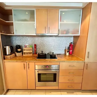 a kitchen with wooden cabinets and a stove at Marina Oasis JBR Beach in Dubai