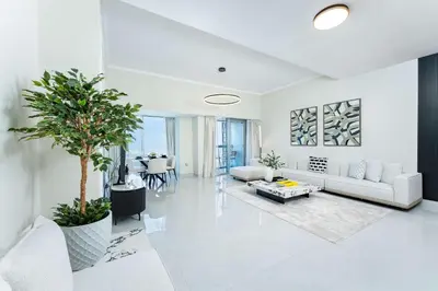 a living room with white furniture and a palm tree at PVH - Iconic Waterfront Escape - Luxury 2BR with Sea Views - DUBAI MARINA in Dubai