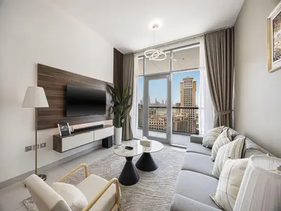 a living room with a couch and a tv at Livin' Holidays - 2BR - Skyline View with Burj Glimpse in Dubai