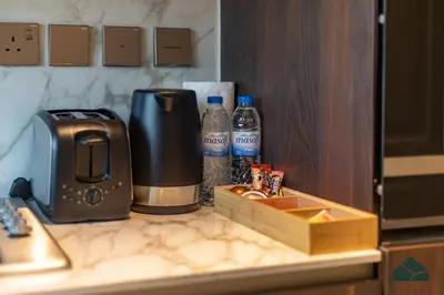 a counter with a coffee maker and two bottles of water at Chic 1BR, Next to Metro by BMS in Dubai