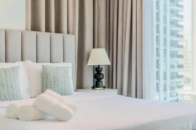 a bedroom with a white bed with a lamp and a window at TRPS - Downtown Views II T2, Downtown Dubai - Modern 3BR Home, Maids Room, Full Burj Khalifa View in Dubai