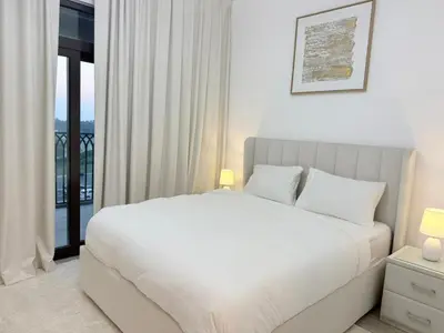 a white bedroom with a bed and a balcony at Stunning 3BR Retreat with Panoramic Sunset Views in Dubai