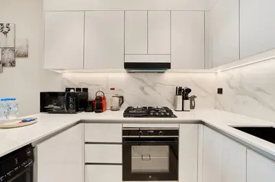 a white kitchen with white cabinets and a stove at Elegant 2BR Ground Floor Escape in Binghatti Galaxy JVC in Dubai