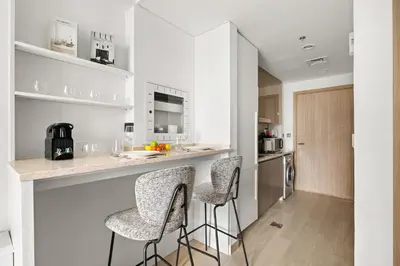 a kitchen with a counter and two stools at a bar at Chic Modern Studio in Meydan Azizi Riviera 26 in Dubai