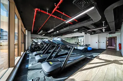 a gym with rows of treadmills and machines at 10 min to Dubai Marina - New Cozy 1 Bed in JVT in Dubai