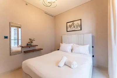 a bedroom with a white bed with two towels on it at HAVN - 1 bedroom in Sobha Creek, MBR City in Dubai
