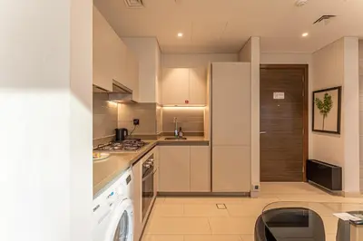 a kitchen with white cabinets and a washer and dryer at HAVN - 1 bedroom in Sobha Creek, MBR City in Dubai