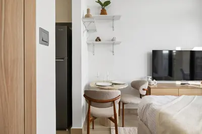 a bedroom with a small table and a kitchen at Bright Modern Studio in Meydan Azizi Riviera 40 in Dubai