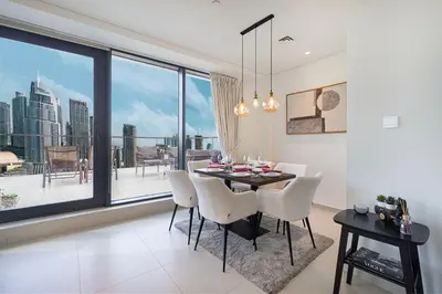 a dining room with a table and chairs and a large window at Luxury Downtown 2 Bedroom Apartment with amazing Burj and Fountain Views and Private Jacuzzi on a large Terrace in Dubai