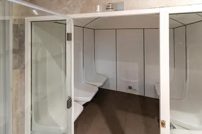 a bathroom with a glass shower and two toilets at Spacious apt City view Gym and pool in Dubai