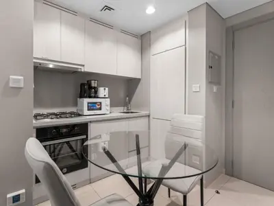 a kitchen with a glass table and white cabinets at Zada Glam Sleek 1BDR Retreat-Business Bay-25 in Dubai