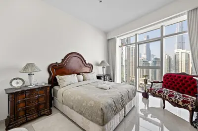 a bedroom with a bed and a chair and a large window at Elegant 3 BR plus Maids Infinity Pool Burj View in Dubai