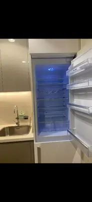 an empty refrigerator with its door open next to a sink at Holiday homes azizi riviera in Dubai