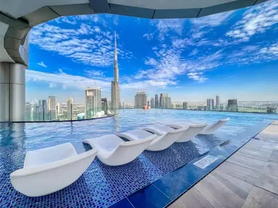 a infinity pool with white chairs in a city skyline at Gogoto5 1BR Burj View Infinity Pool High Floor in Dubai