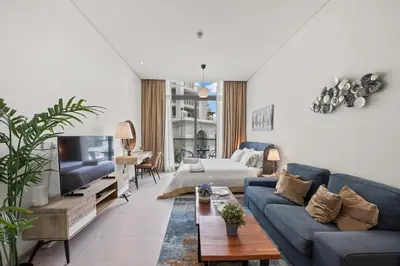 a living room with a blue couch and a tv at Luxury Studio with Balcony in JVC in Dubai