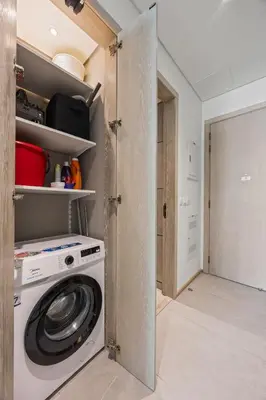a washing machine in a kitchen with a door open at Luxury Studio with Balcony in JVC in Dubai
