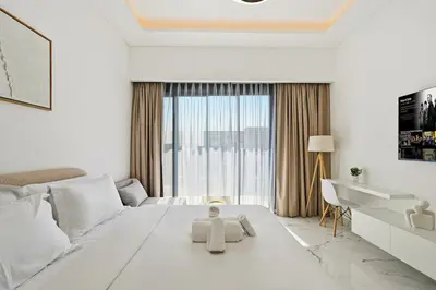 a white bedroom with a large white bed and a desk at Estudio Pearl en Dubai by beBalmy in Dubai