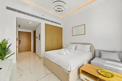 a white bedroom with a bed and a couch at Estudio Pearl en Dubai by beBalmy in Dubai