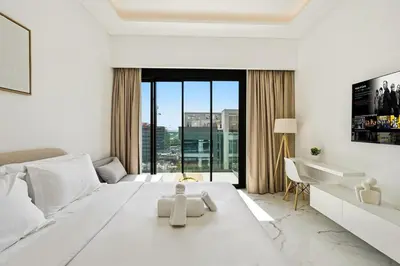 a white bedroom with a large bed and a large window at Estudio Pearl en Dubai by beBalmy in Dubai
