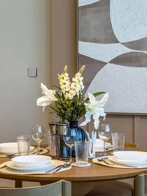 a table with plates and glasses and a vase of flowers at Designer's Selection - Luxury in the Heart of DIFC in Dubai