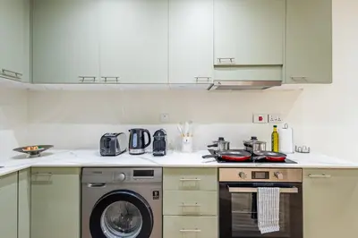 a kitchen with a stove and a washing machine at Designer's Selection - Luxury in the Heart of DIFC in Dubai