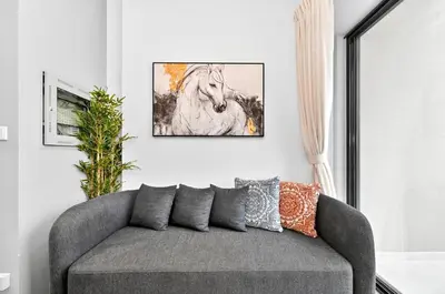 a couch in a living room with a painting of a horse at Golden Stays - Cozy 1BR Retreat I Skyline Views & Urban Charm in Dubai