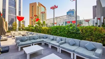a rooftop patio with couches and tables in a city at TRPS - MAG 318, Business Bay - Spacious 1BR plus Maids, Furnished, City View in Dubai