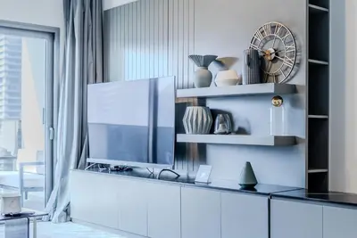 a living room with a tv on a white cabinet at TRPS - MAG 318, Business Bay - Spacious 1BR plus Maids, Furnished, City View in Dubai