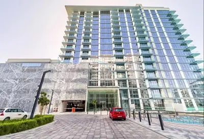 a red car parked in front of a tall building at Glimpse of Burj Khalifa 2BR, 15-Minute Drive to Burj Khalifa and Downtown Landmarks, District One Phase III Residences 13, Mohammed Bin Rashid Al Maktoum City by Deluxe Holiday Homes in Dubai