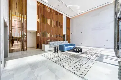 a lobby with a blue couch and a table at Glimpse of Burj Khalifa 2BR, 15-Minute Drive to Burj Khalifa and Downtown Landmarks, District One Phase III Residences 13, Mohammed Bin Rashid Al Maktoum City by Deluxe Holiday Homes in Dubai