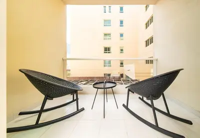 two chairs and a table on a balcony with a building at Stunning 1 Bed in Al Dhafra 2 The Greens in Dubai