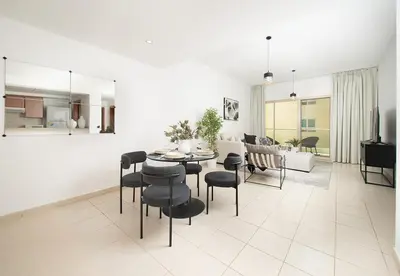 a dining room and living room with a table and chairs at Stunning 1 Bed in Al Dhafra 2 The Greens in Dubai