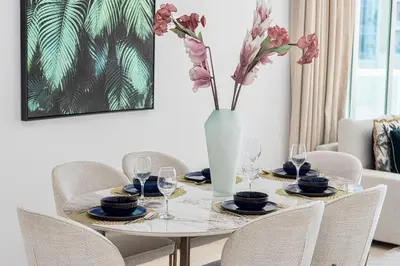 a table with chairs and a vase with flowers on it at Luxury Marina Views Near Mall & Beach, with Gym, Swimming Pool & Car Park in Dubai