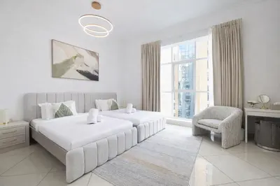 a white bedroom with two beds and a chair at Luxury Marina Views Near Mall & Beach, with Gym, Swimming Pool & Car Park in Dubai