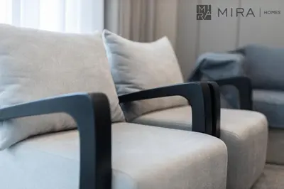 a couch and a chair in a living room at Mira Holiday Homes - High View 2 Bed Oasis at Nobles Tower with Sauna in Dubai