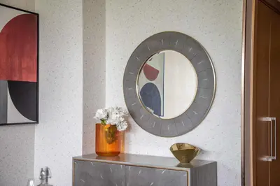 a mirror on a wall with a vase of flowers on a table at Frank Porter - Burj Vista Tower 2 in Dubai