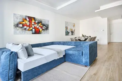 a living room with a blue couch and a painting at Frank Porter - Marina Diamond 4 in Dubai