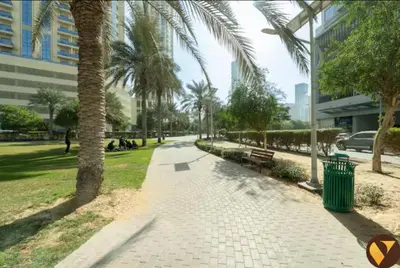 a sidewalk with a palm tree and a trash can at Vogue JVC Jeewar Tower Near Circle Mall, One Bedroom Apartment with Balcony and City View, Access to all Amenities in Dubai