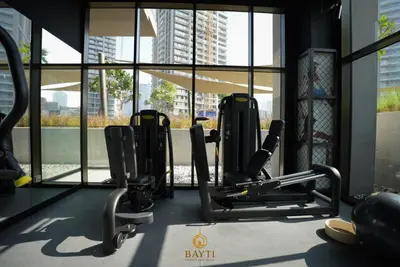 a gym with cardio equipment in a building with windows at Evasion Moderne a Business Bay vue sur le canal in Dubai