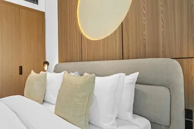 a bedroom with a bed and a couch and pillows at Minimalist Studio in Binghatti Azure in Dubai