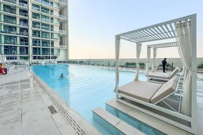 a hotel swimming pool with a chair in the water at Minimalist Studio in Binghatti Azure in Dubai