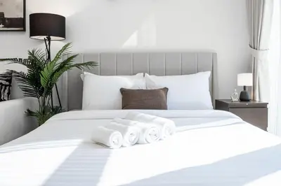 a white bed with three rolled towels on it at Azizi Riviera 5, Meydan Close to Downtown - Onelink in Dubai