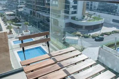 a wooden bench sitting on top of a building with a pool at Azizi Riviera 5, Meydan Close to Downtown - Onelink in Dubai