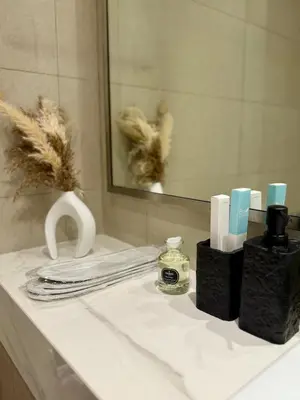 a bathroom counter with a sink with towels and a mirror at Azizi Riviera Studio High Floor Partial Burj View in Dubai