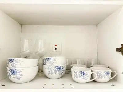 a shelf with blue and white cups and glasses at Azizi Riviera Studio High Floor Partial Burj View in Dubai